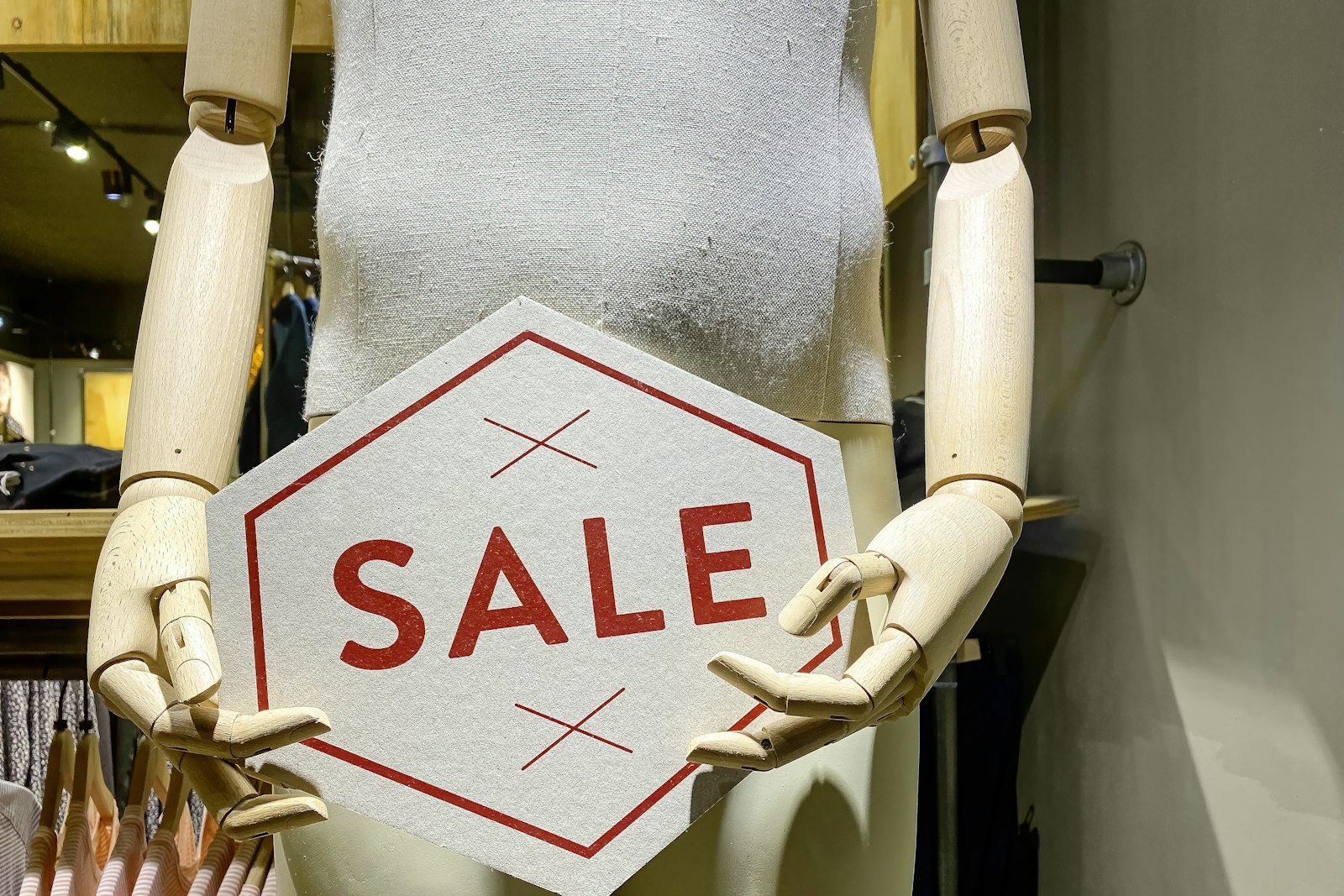 A shop mannequin holding a sale sign