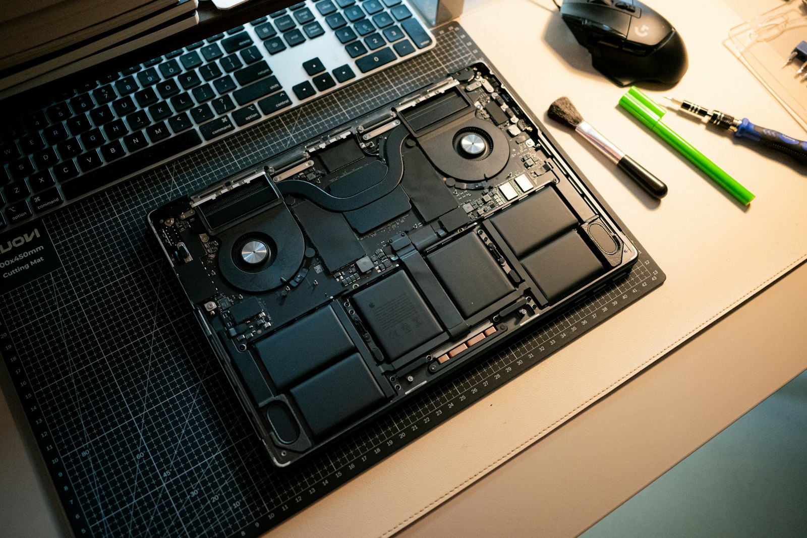 An open laptop with its internal components exposed on a workbench