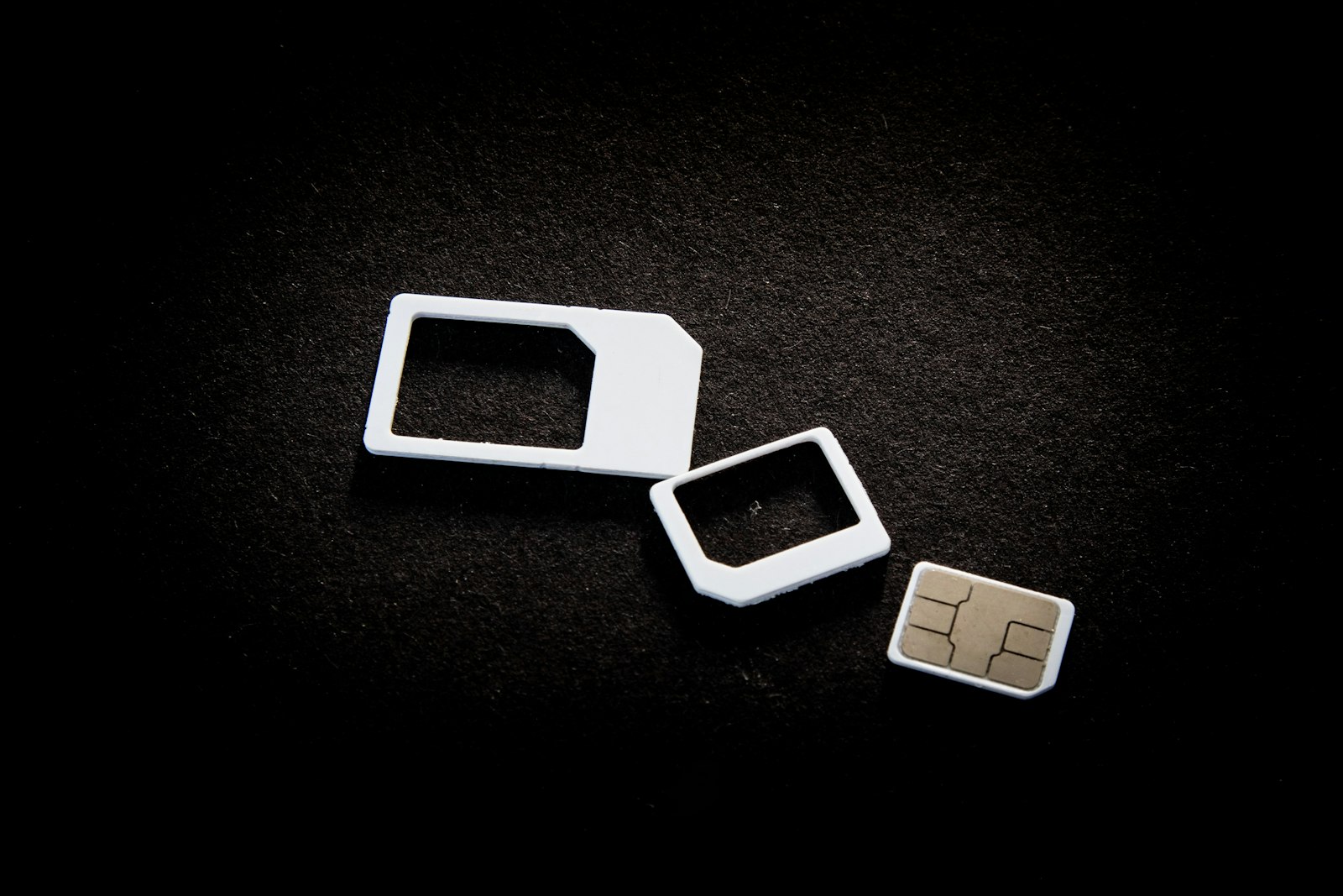 SIM cards and their adapters on a dark surface