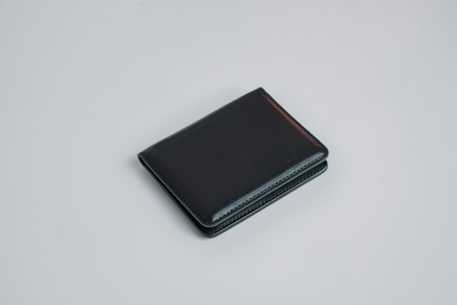 A closed black wallet on a plain table