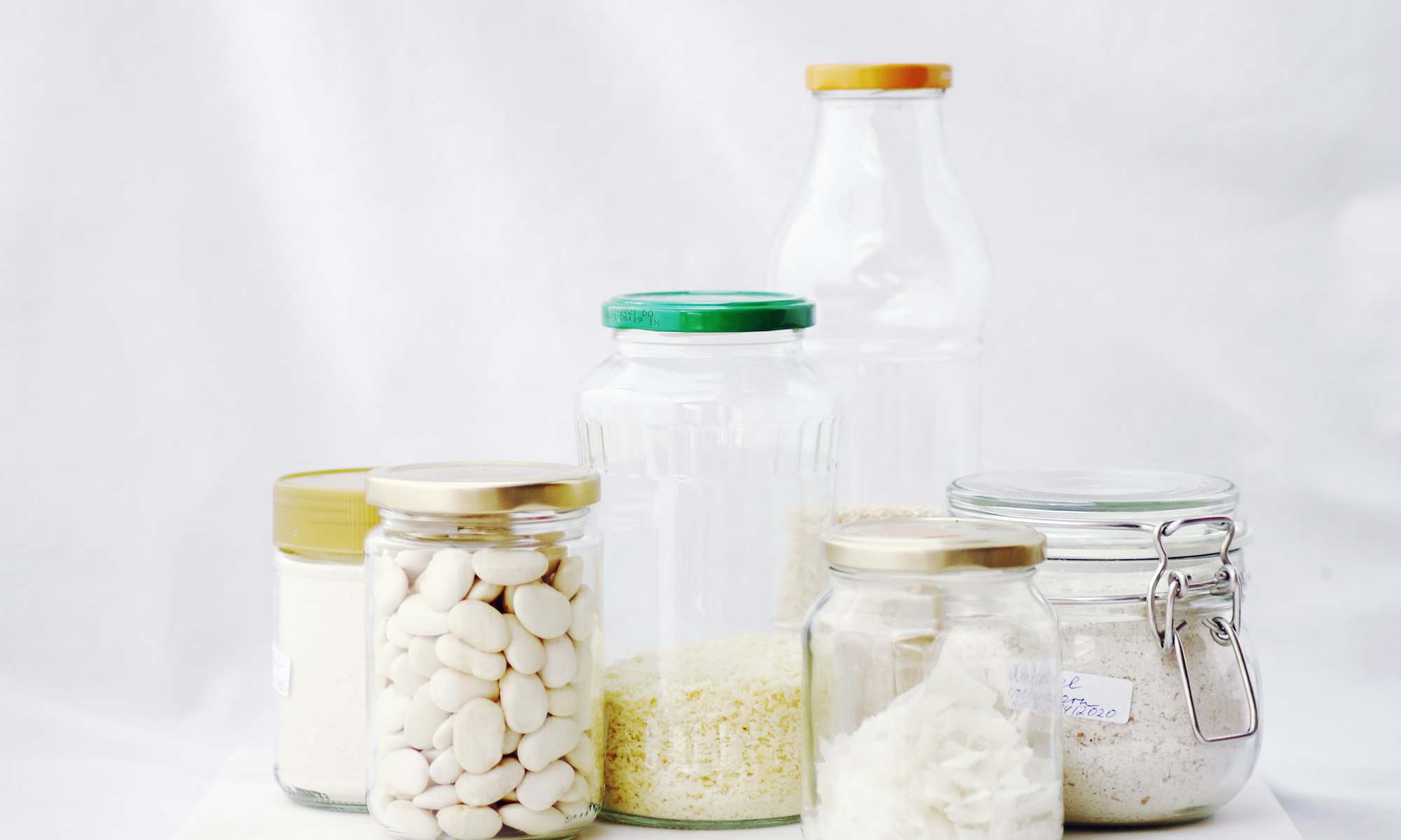Glass jars of pantry staples on a white table