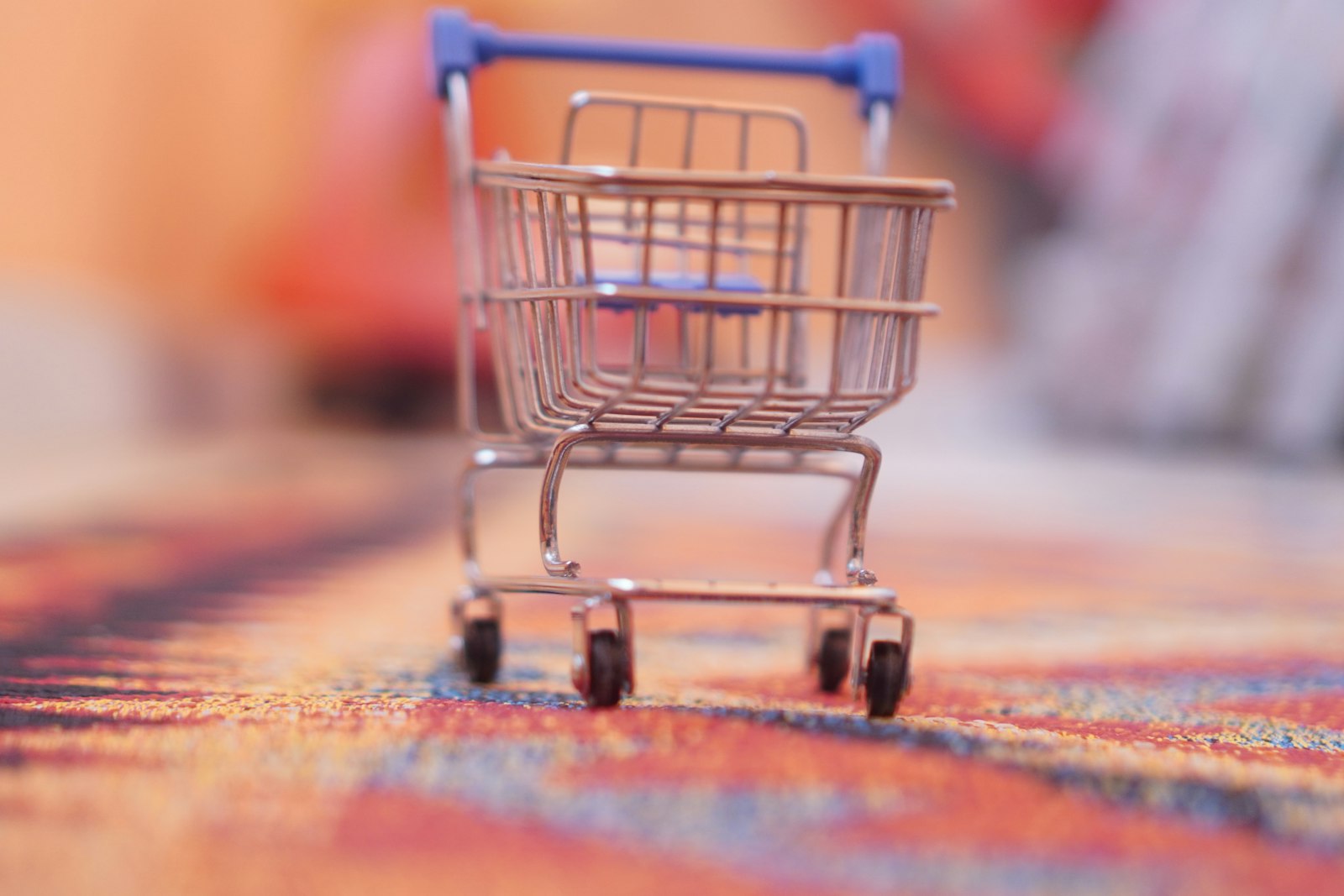 A miniature shopping cart on a patterned rug